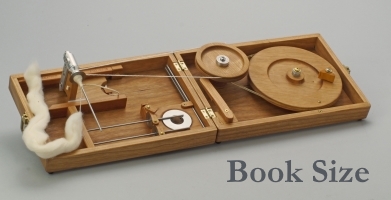 Book size spinning charkha with piece of wool
